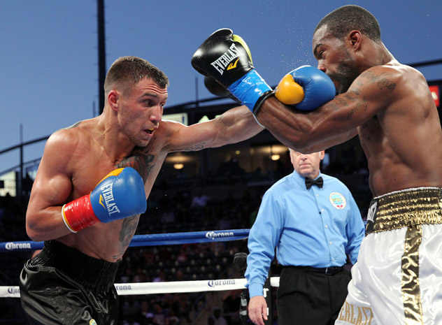Vasyl Lomachenko (L) punches Gary Russell Jr. on his way to winning a world title in his third pro fight. Photo by Chris Farina/Top Rank