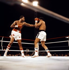 Holmes (L) tags Muhammad Ali. Photo: THE RING